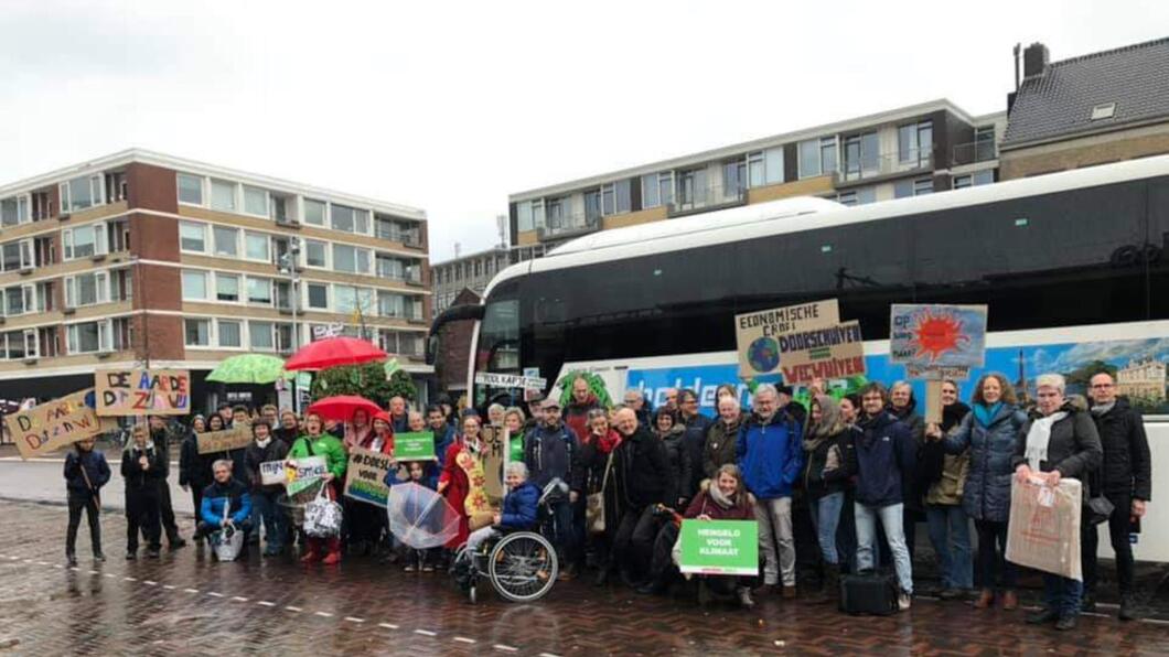 GroenLinksers met protestborden bij de bus