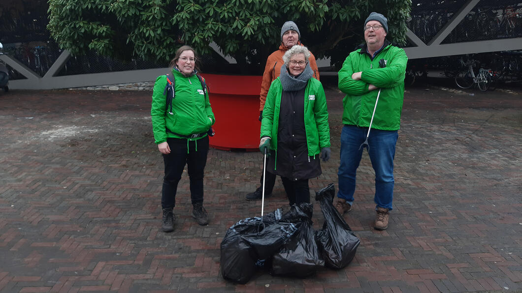 4 mensen, waarvan 3 met GroenLinks-jasjes, met aan hun voeten een paar volle vuilniszakken © Charlotte Bax
