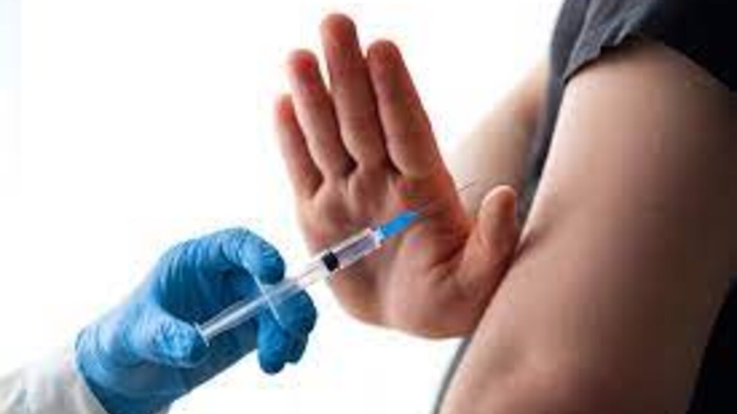 hand in blauwe handschoen met vaccinatieprik wordt tegengehouden om in een ontblote arm te prikken.