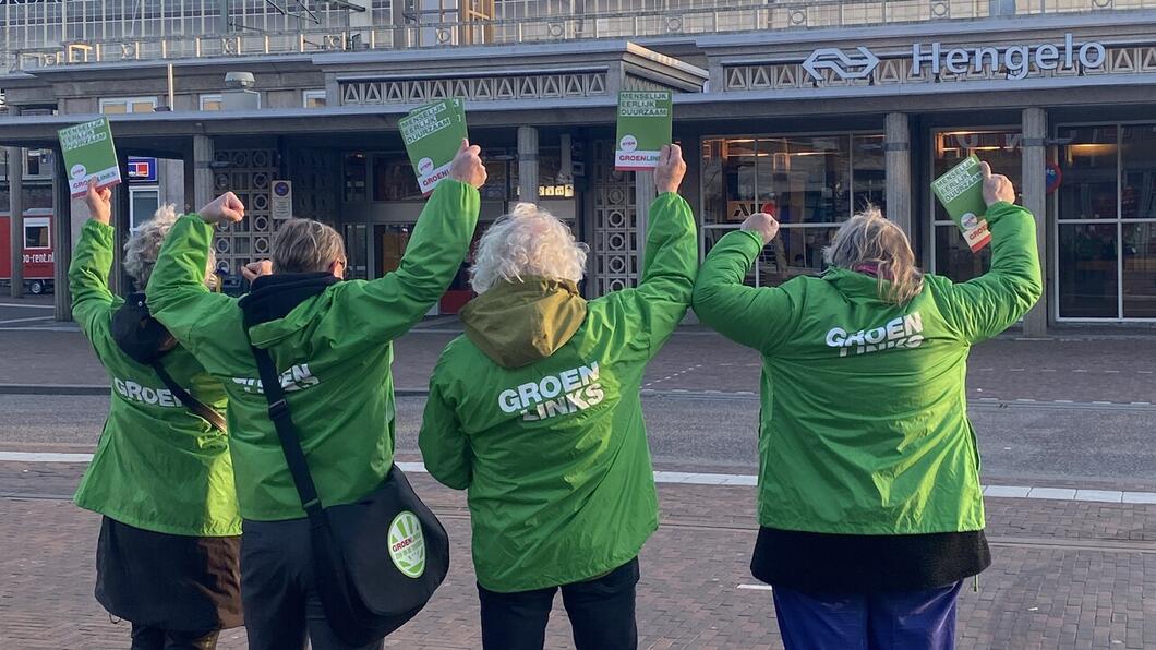 GroenLinksers juichend op de rug gefotografeerd met station Hengelo op de achtergrond