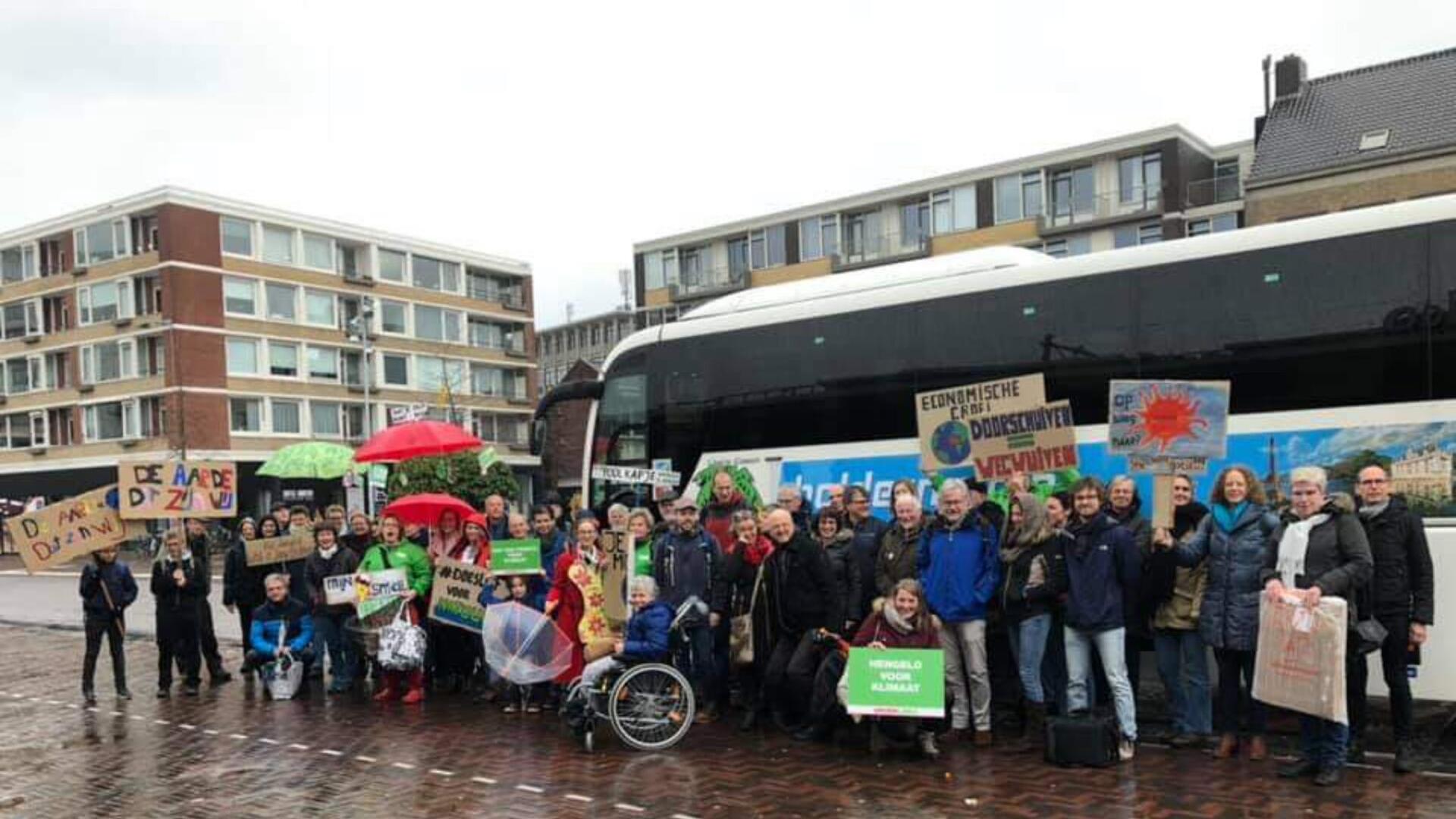GroenLinksers met protestborden bij de bus